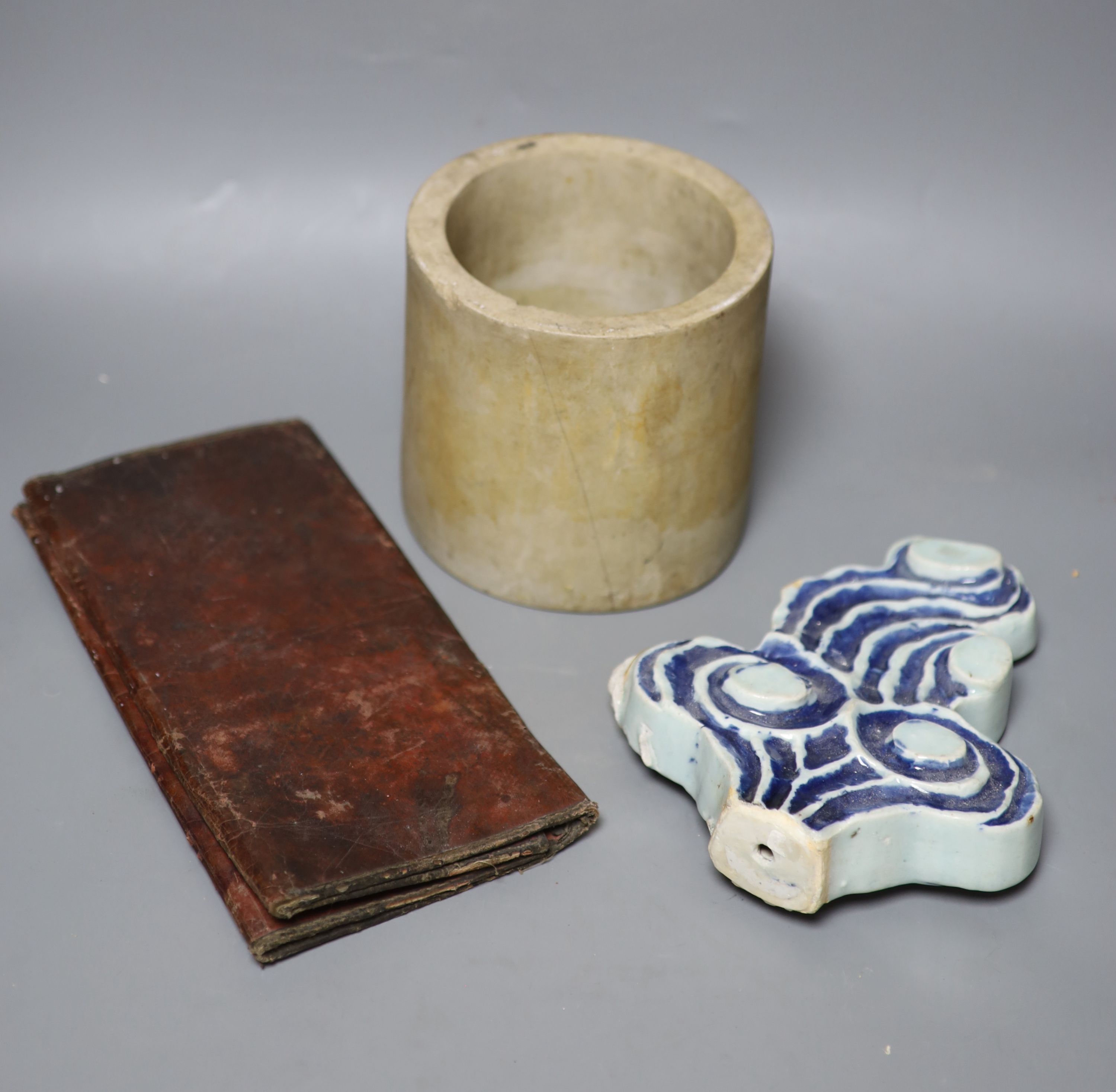 A Chinese blue and white Ming porcelain finial, a leather wallet. c.1920 and a cream stone cylinder, longest 29cm